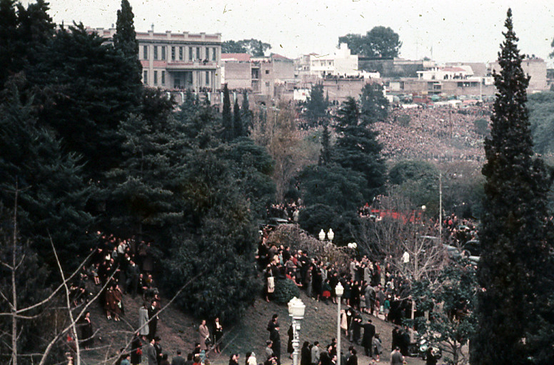 Multitud dispersa entre la arboleda de la barranca al río.