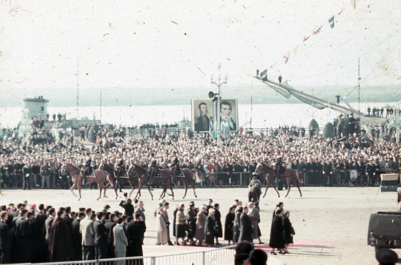 Desfile de caballería con los retratos de San Martín y Belgrano junto al río.
