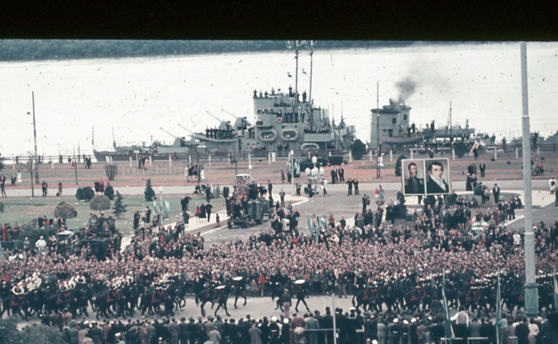 Desfile de tropas frente al publico, con retratos de San Martín y Belgrano y buque ARA La Argentina sobre el Río Paraná, Rosario, 1957.